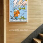 A 'Don't Spit' behaviour safety poster (Code: BSP-12) framed and displayed on a wooden slat wall near a staircase. The poster features a cartoon illustration of a man being pointed at by three giant fingers while standing in a puddle of water/spit. The poster's message clearly states, 'Hey!! Don't Spit...' in English and 'थूके नहीं...' in Hindi, promoting cleanliness and hygiene.