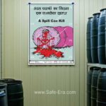 Safe-Era Chemical Spill Hazard Poster CSP-2 in a factory setting, featuring a cartoon of a leaking pink chemical barrel and a skull-shaped spill with "A Spill Can Kill" warning.
